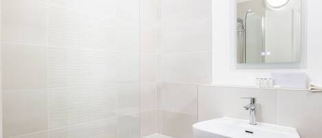 A modern bathroom with a glass-enclosed shower, a white sink, and a mirror above it.