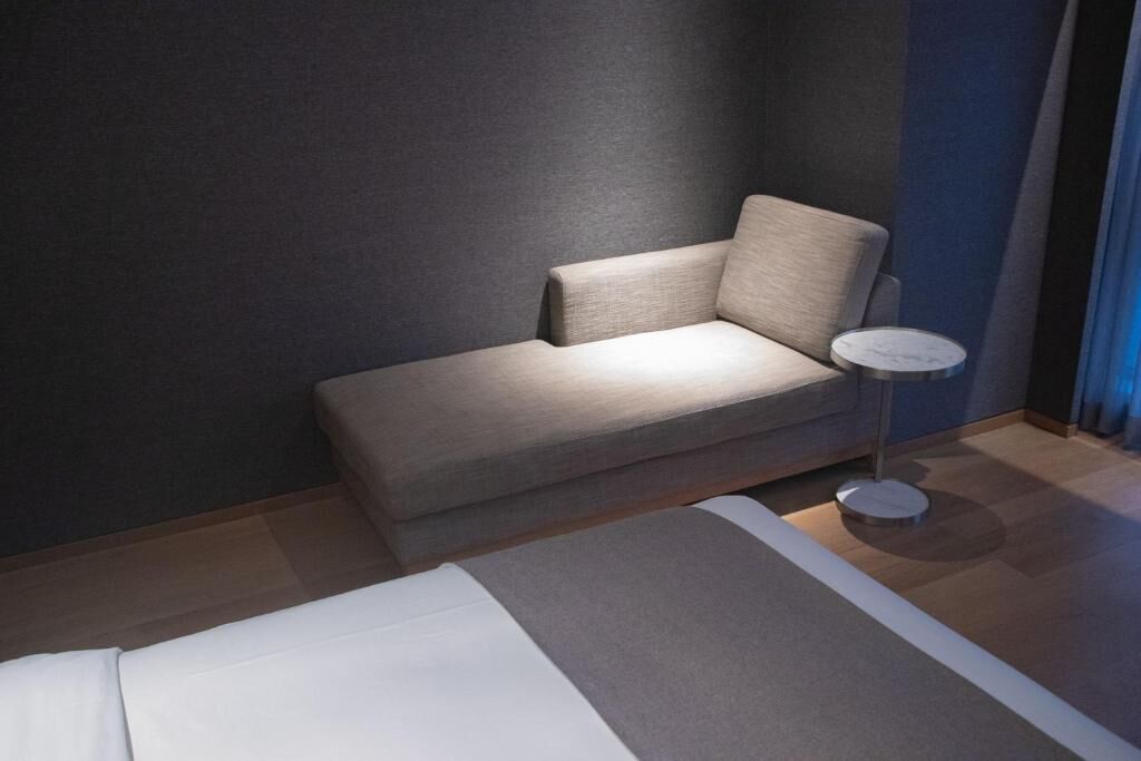 A modern hotel room with a sofa, a small round table, and a bed.