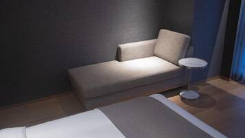 A modern hotel room with a sofa, a small round table, and a bed.