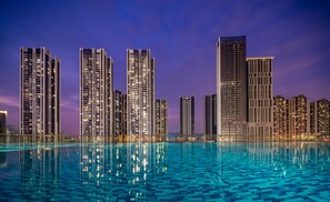 A nighttime cityscape with high-rise buildings and a reflective pool. - Genpla Hotel Shenzhen NanShan University Town (Shenzhen)