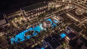 A resort with multiple swimming pools, palm trees, and well-lit outdoor areas. - Shilla Monogram Danang (Da Nang)
