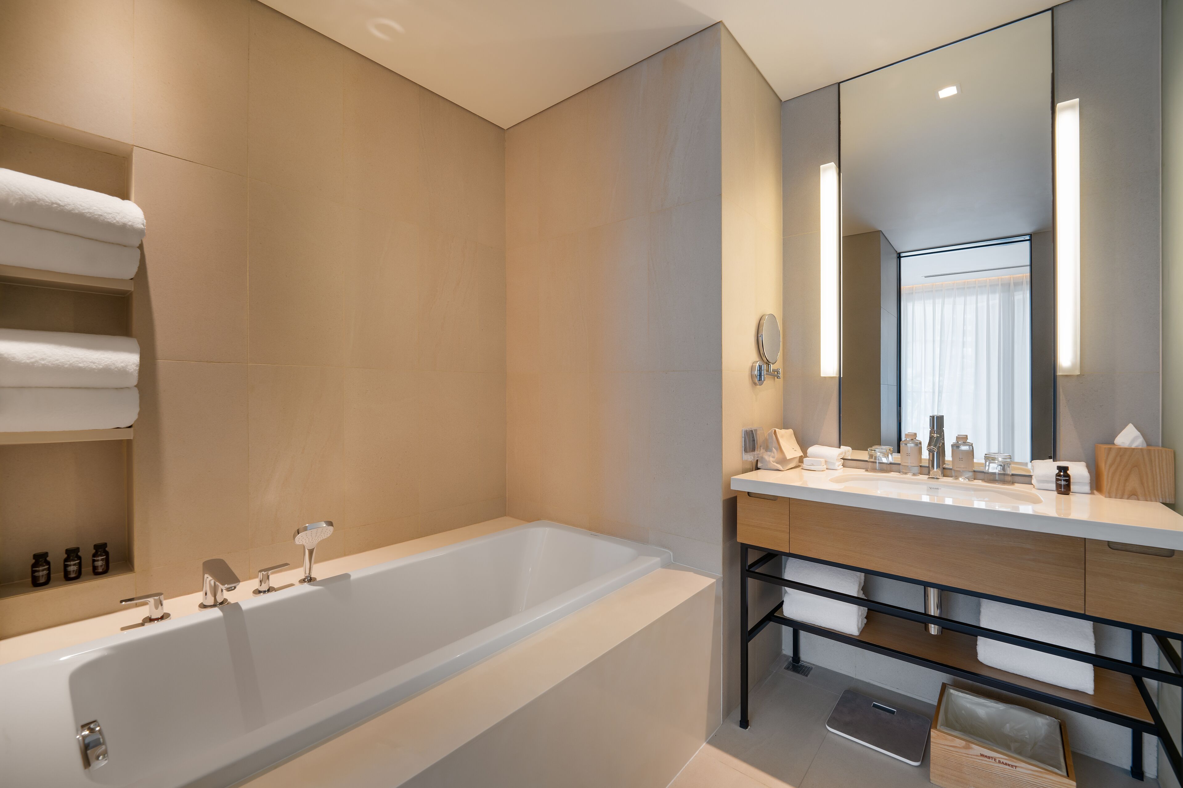 A modern bathroom with a large bathtub, a vanity with a mirror, and neatly arranged towels.