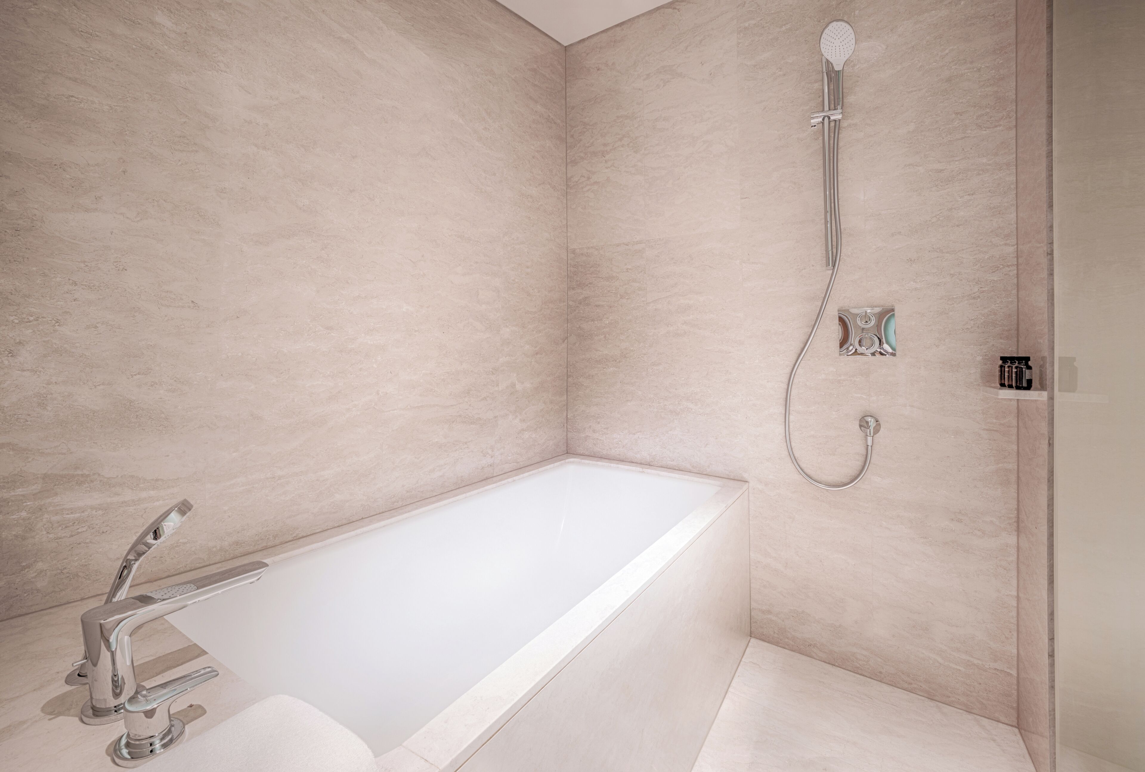 A modern bathroom with a freestanding bathtub, a handheld showerhead, and a wall-mounted faucet.