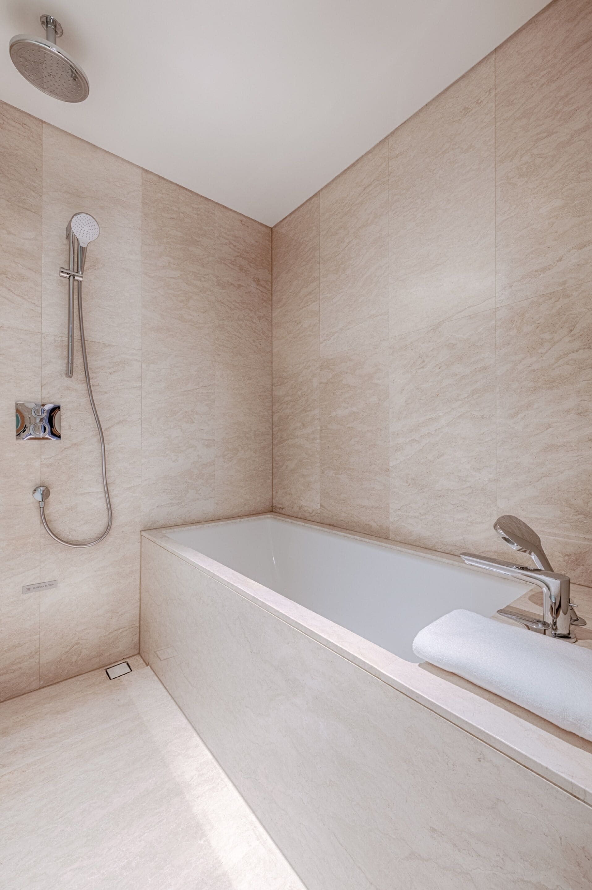 Un baño moderno con una bañera independiente, un cabezal de ducha manual y un grifo de pared.