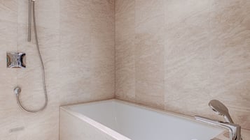 Un baño moderno con una bañera independiente, un cabezal de ducha manual y un grifo de pared.