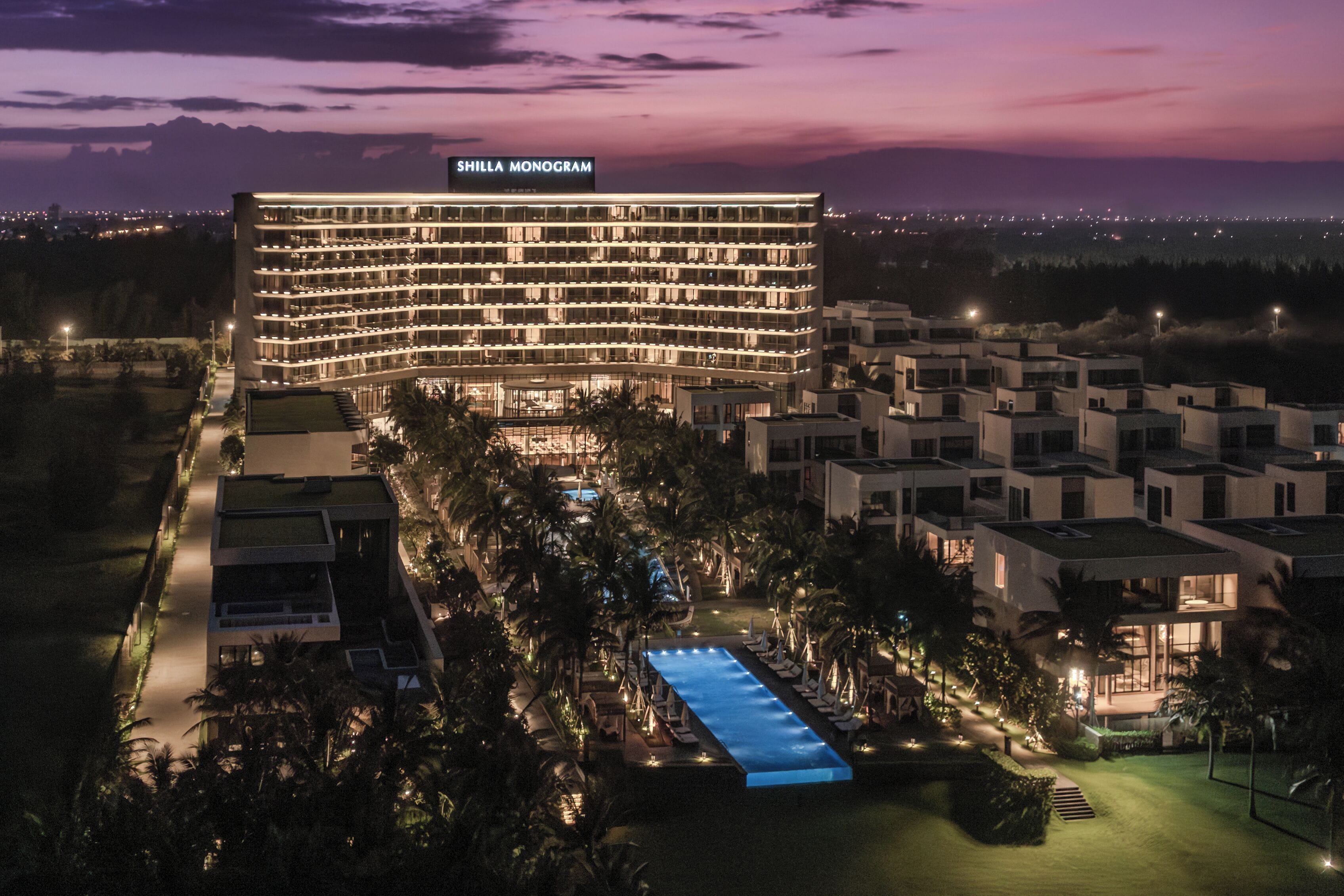 A hotel with a pool, surrounded by palm trees and modern architecture.
