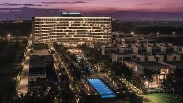 A hotel with a pool, surrounded by palm trees and modern architecture.