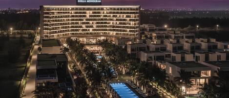 A hotel with a pool, surrounded by palm trees and modern architecture.