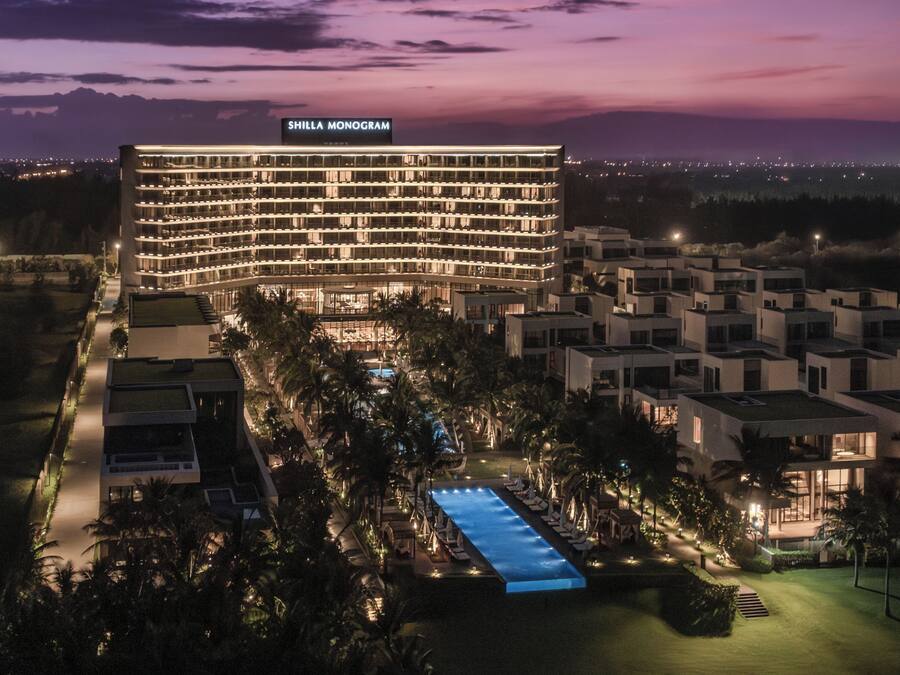 A hotel with a pool, surrounded by palm trees and modern architecture.