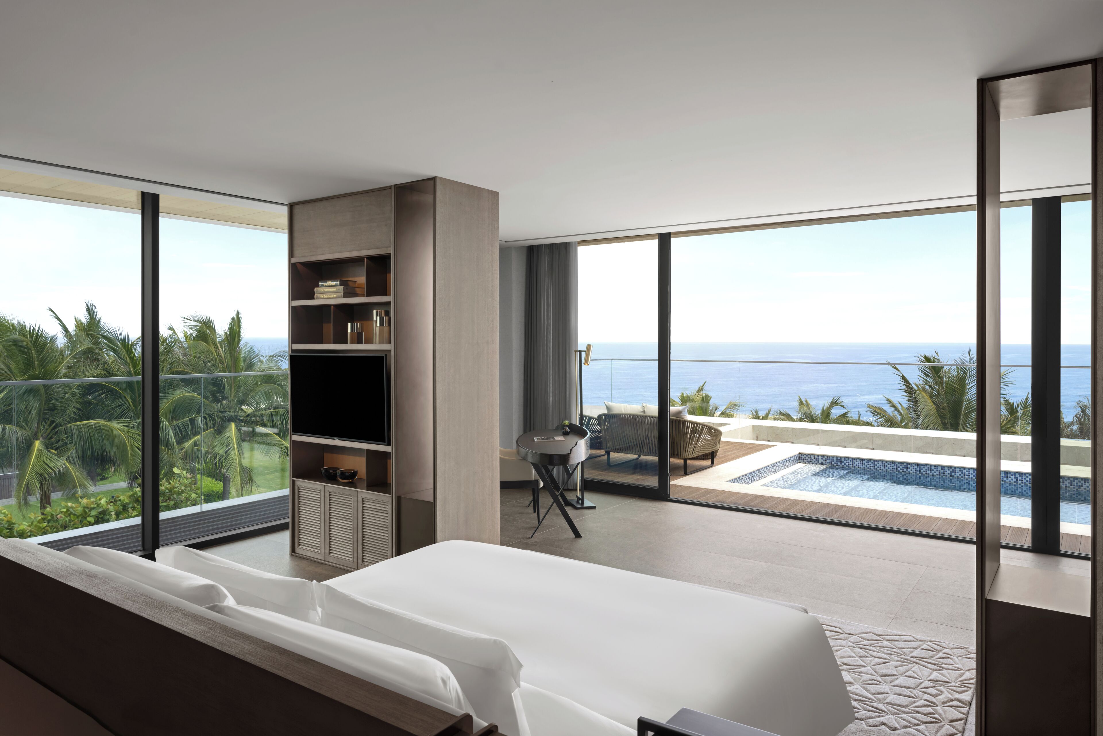 Una habitación de hotel moderna con una cama grande, un escritorio pequeño y vistas al océano.