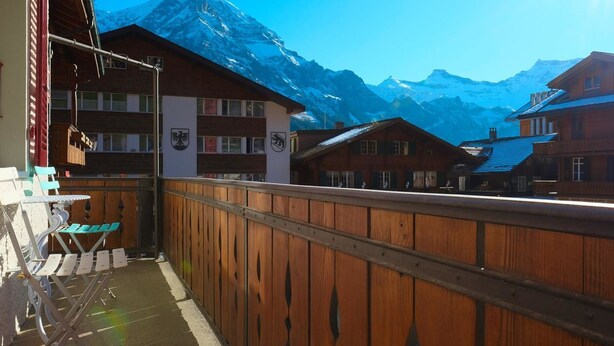 Een houten balkon met uitzicht op besneeuwde bergen.