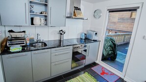 Een moderne keuken met grijze kastjes, een inbouwoven en een koffiezetapparaat.