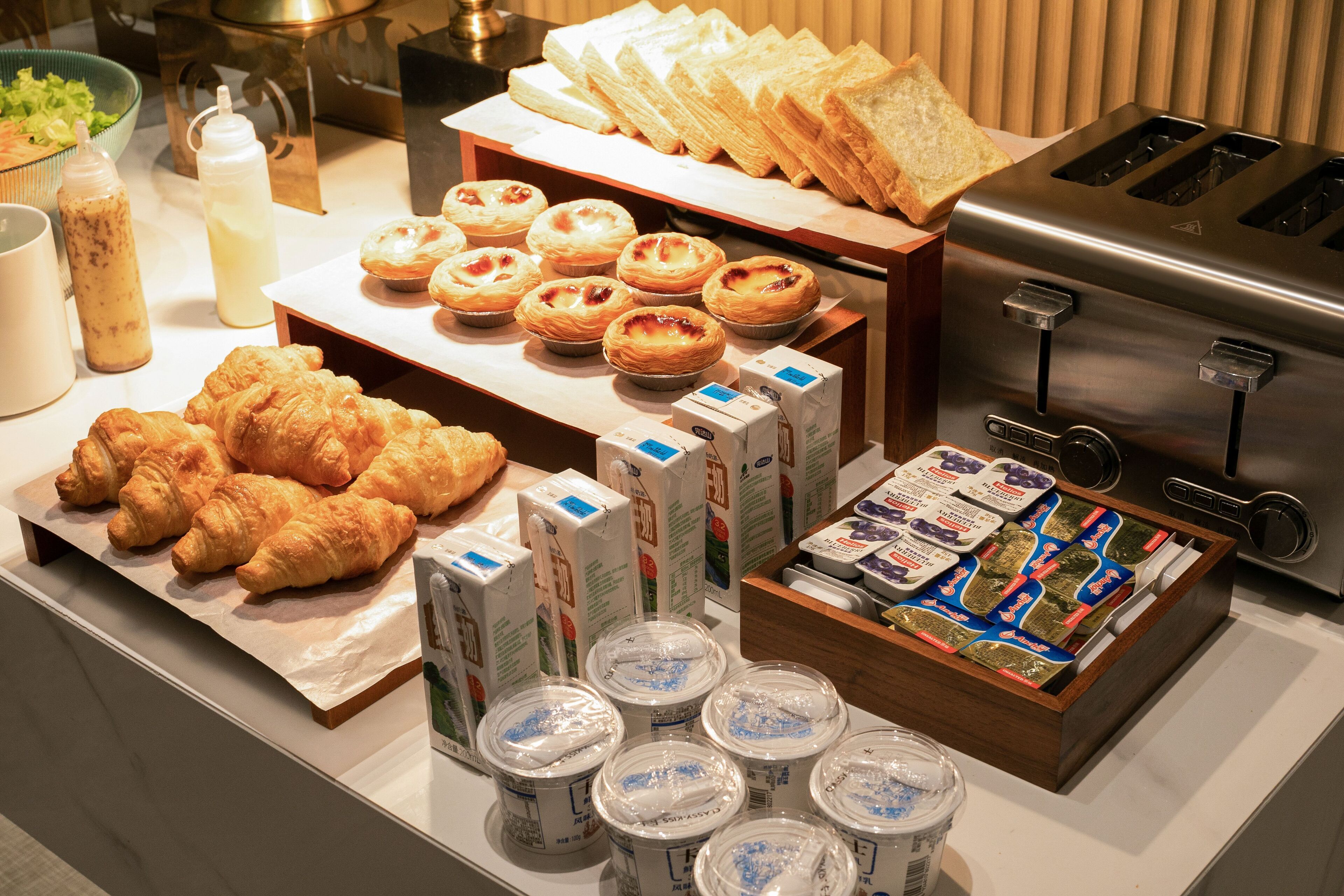 A breakfast buffet with pastries, bread, and dairy products.