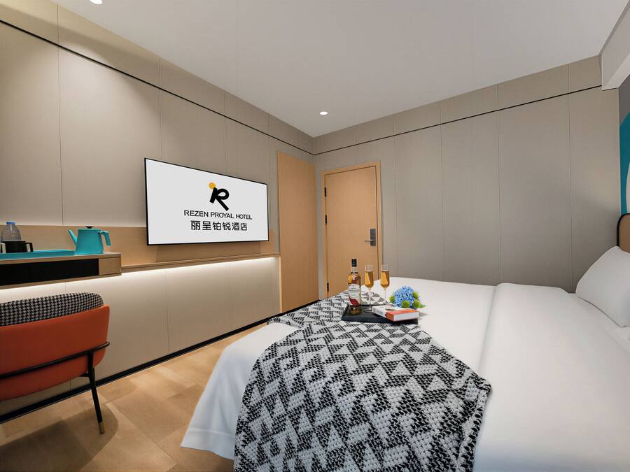 Habitación de hotel con cama, escritorio, silla, televisor y una obra de arte colgada en la pared.