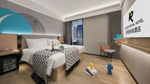 Una habitación de hotel moderna con cama, mesita de noche, minibar y vistas a la ciudad.