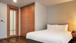 A hotel room with a large bed, a wardrobe, and a bedside table with a phone. - Ramada Hotel and Suite Seoul Namdaemun (Seoul)