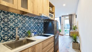 Una cocina moderna con armarios de madera, un lavamanos de acero inoxidable y un refrigerador negro.
