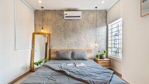 Un dormitorio moderno con una cama gris, cabecera de madera y un espejo grande.