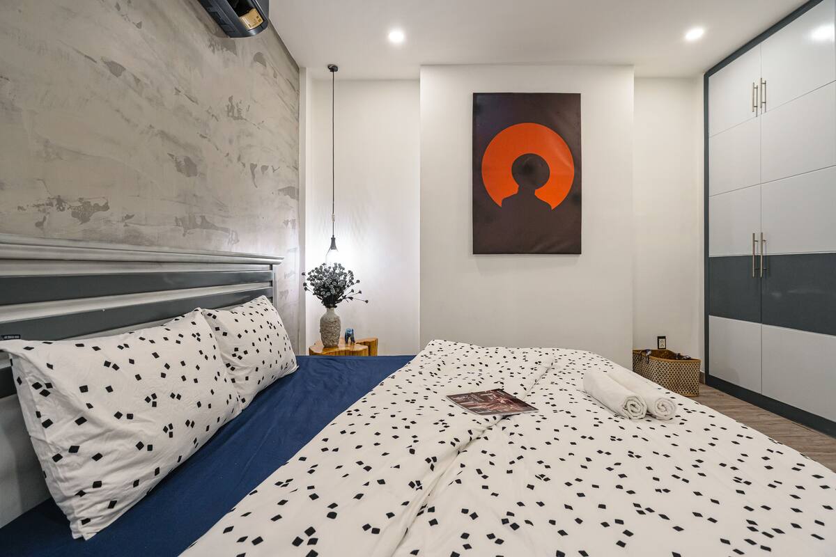 A modern bedroom with a large bed, a wall-mounted artwork, and a wardrobe.