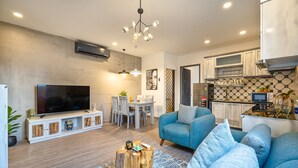 Una sala de estar moderna con televisor, sofá y comedor.