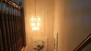 Una escalera de madera con un candelabro de cristal y obras de arte en las paredes.