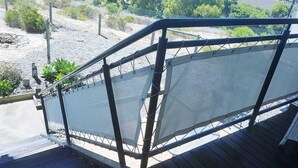 A wooden deck with a metal railing and a mesh screen.