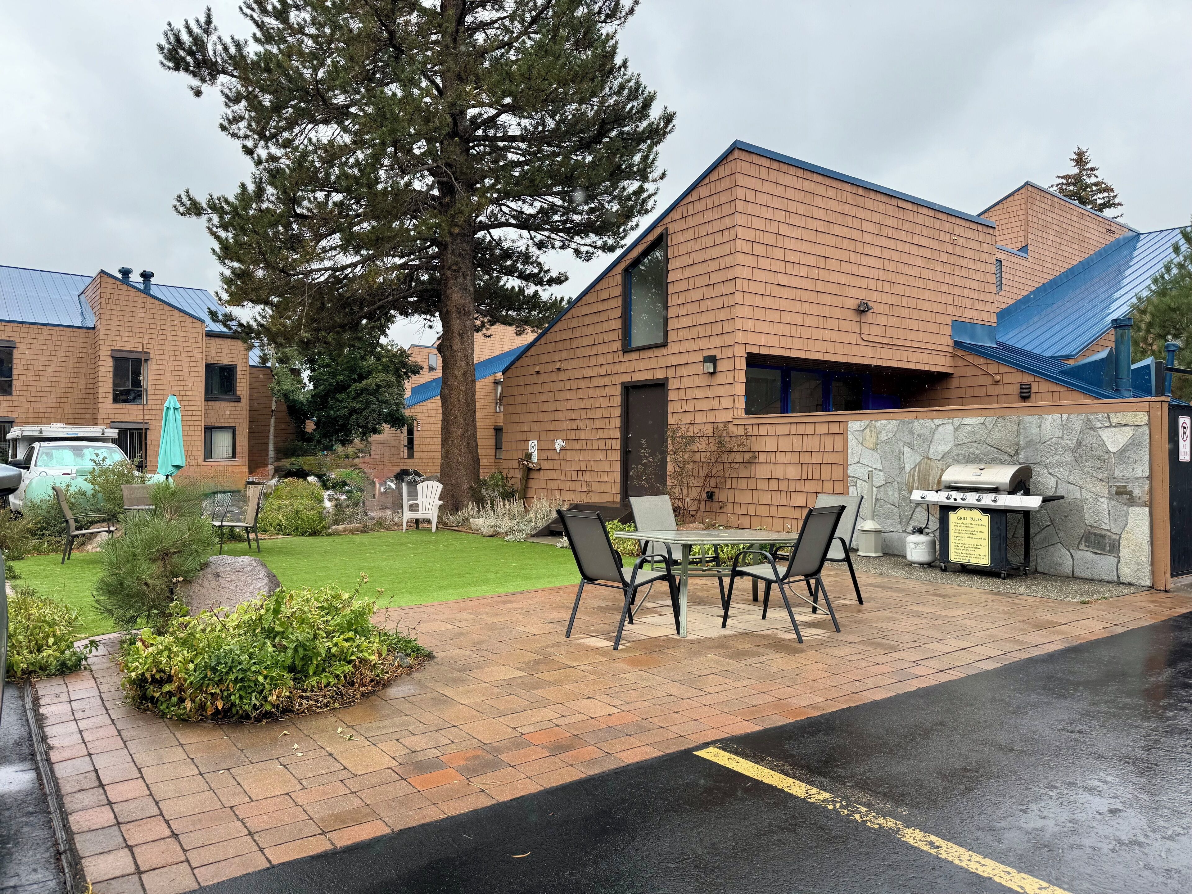 A brick building with a patio area, outdoor seating, and a barbecue grill.