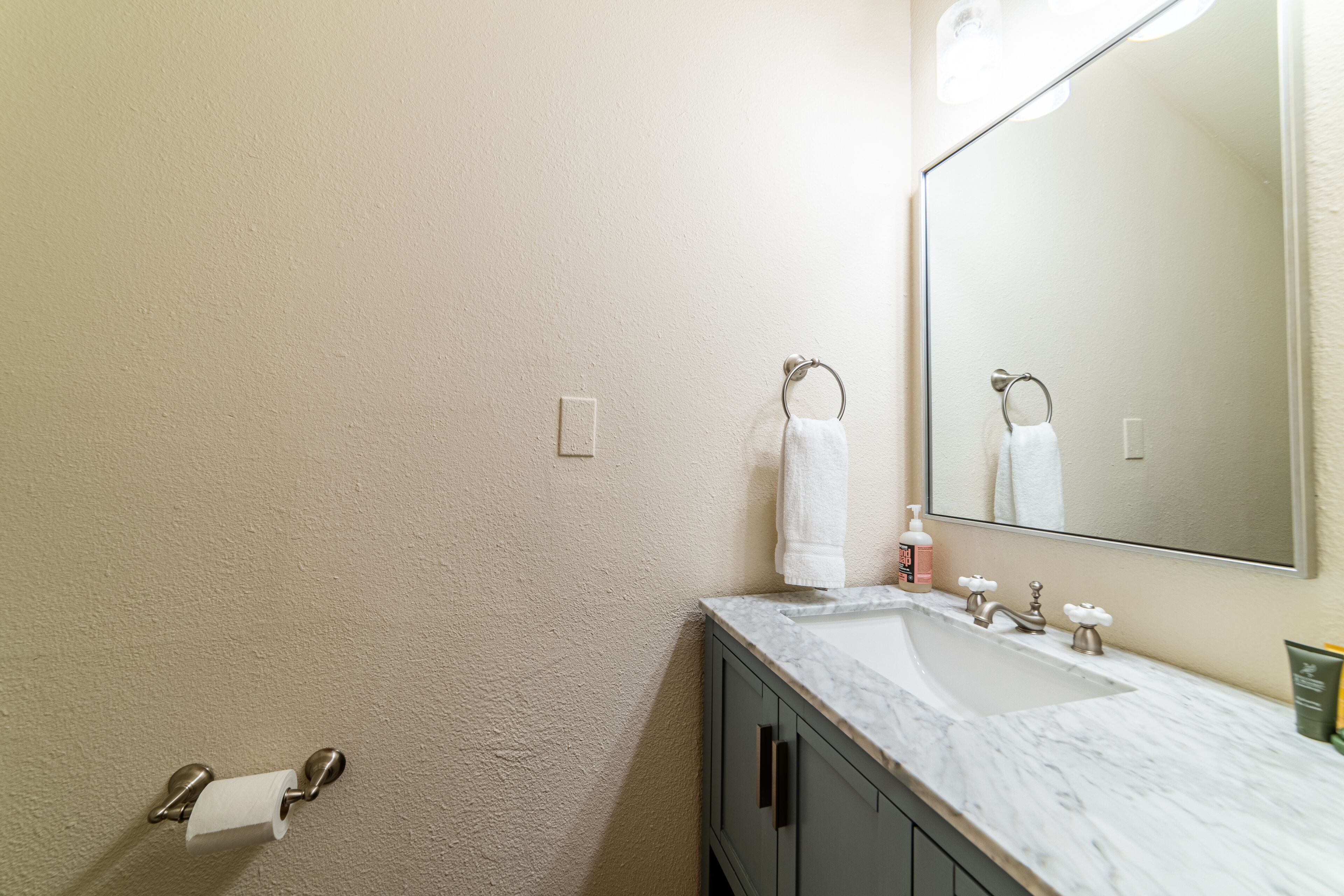 A bathroom with a marble sink, a mirror, and a towel rack.