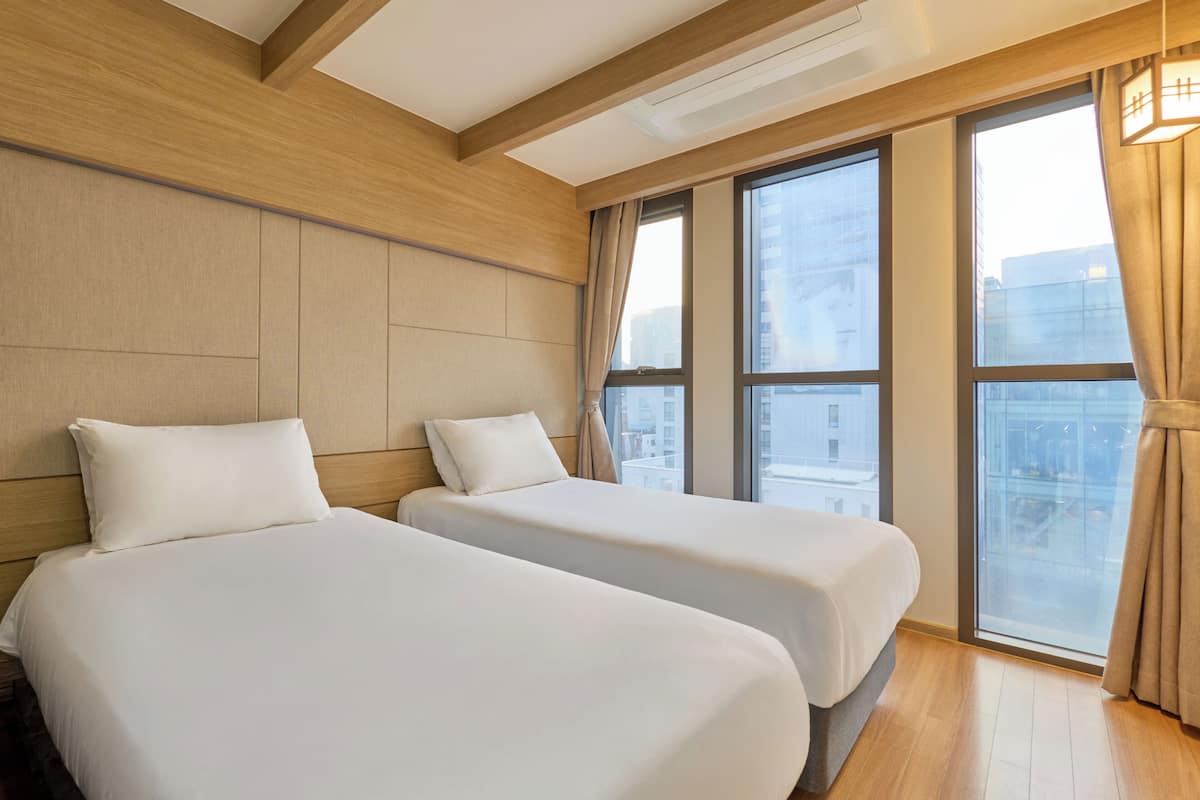 A hotel room with two beds, large windows, and a wooden ceiling.