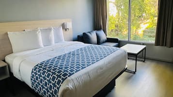 Una camera d'albergo con un letto grande, un comodino, una sedia e una finestra con tende.
