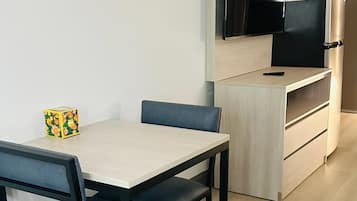 Un angolo cottura compatto con forno a microonde integrato, un tavolino e una sedia.