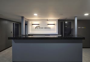 A reception desk with a sign reading "S-Stay Hotel" and directional arrows indicating room numbers 208 to 216. - S Stay Hotel (Suwon)
