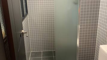 Een badkamer met toilet, douchecabine en betegelde wanden.