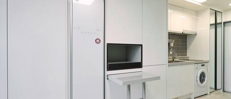 A modern kitchen with a built-in oven, a microwave, and a washing machine.