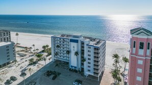 A beachfront hotel with multiple floors, a parking lot, and palm trees. - Top-Floor Gulf Views | Updated Condo Near Beach & Times Square & Pool Access (Fort Myers Beach)