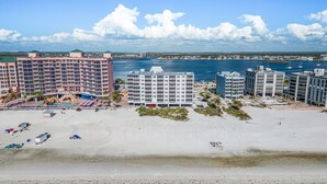 Un hôtel situé en bord de mer, composé de plusieurs bâtiments, doté d’une piscine et d’une plage aménagée avec des parasols et des embarcations.
