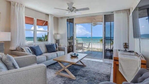 Un salon moderne avec un canapé, une table basse et une vue sur la plage.
