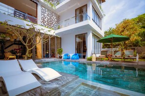 Una piscina al aire libre, sillones reclinables de piscina