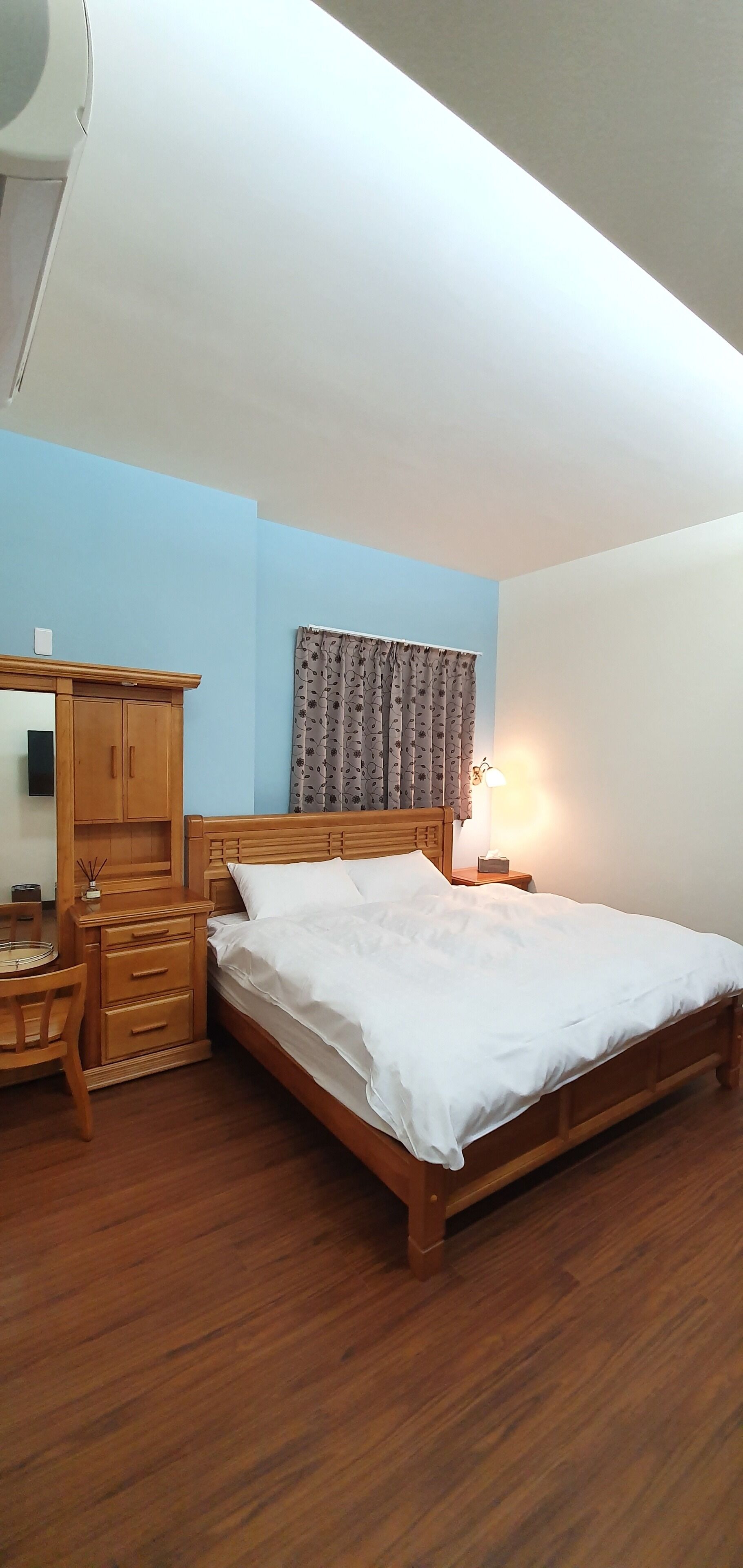A bedroom with a wooden bed, a nightstand, a dresser, and a mirror.