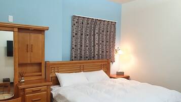 A bedroom with a wooden bed, a nightstand, a dresser, and a mirror.
