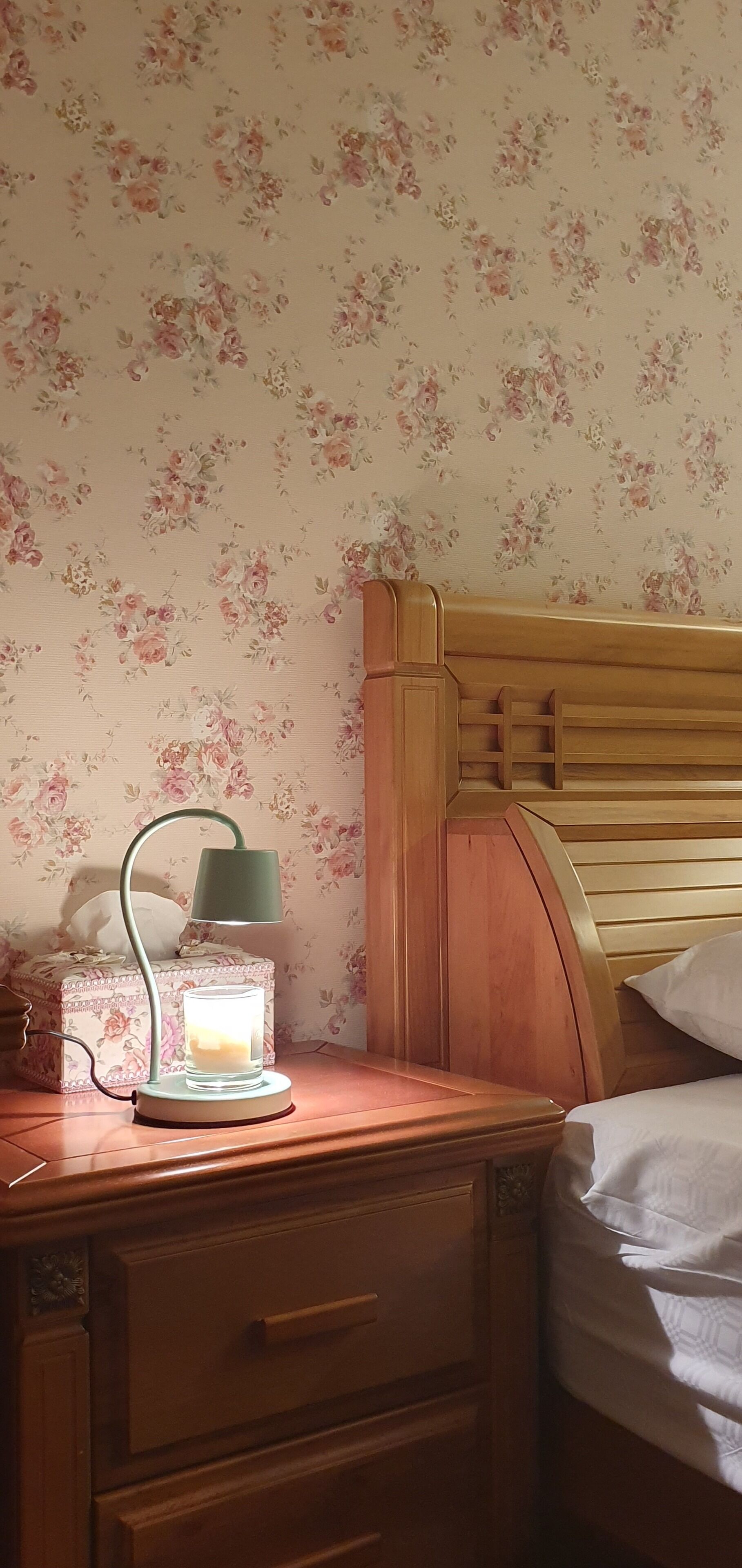 A wooden bedside table with a lamp, a tissue box, and a glass of water.