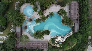 An aerial view of a resort with a large central pool surrounded by palm trees and lounge chairs. - Haikou Yatter Hotel, Vignette Collection by IHG (Haikou)