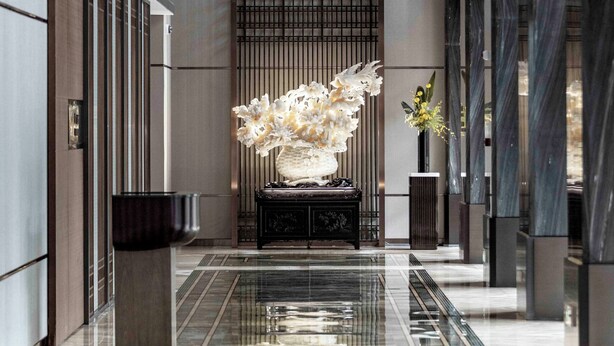 A modern lobby with a reflective marble floor, a central decorative sculpture, and a potted plant. - Haikou Yatter Hotel, Vignette Collection by IHG (Haikou)