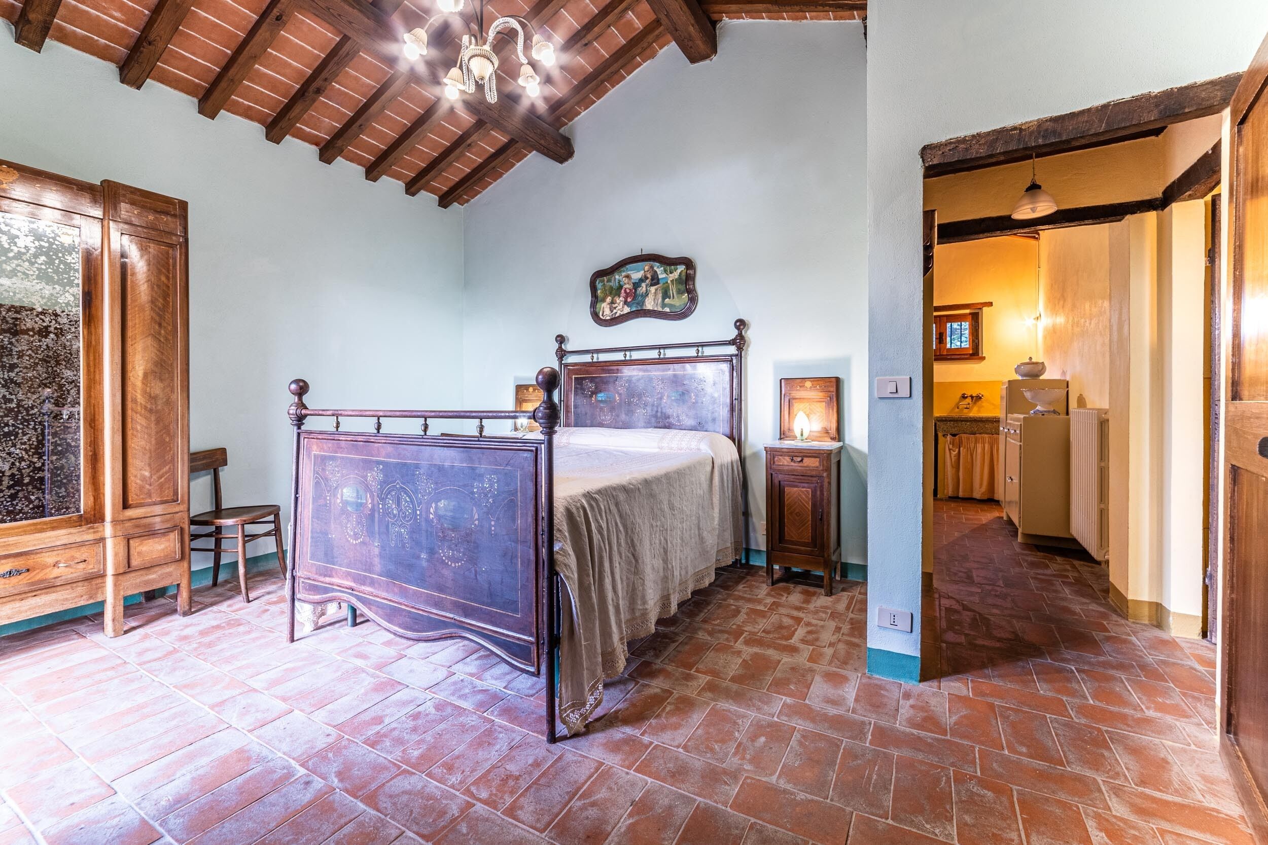 Un dormitorio con una cama de madera, una mesita de noche, una silla y un cuadro en la pared.