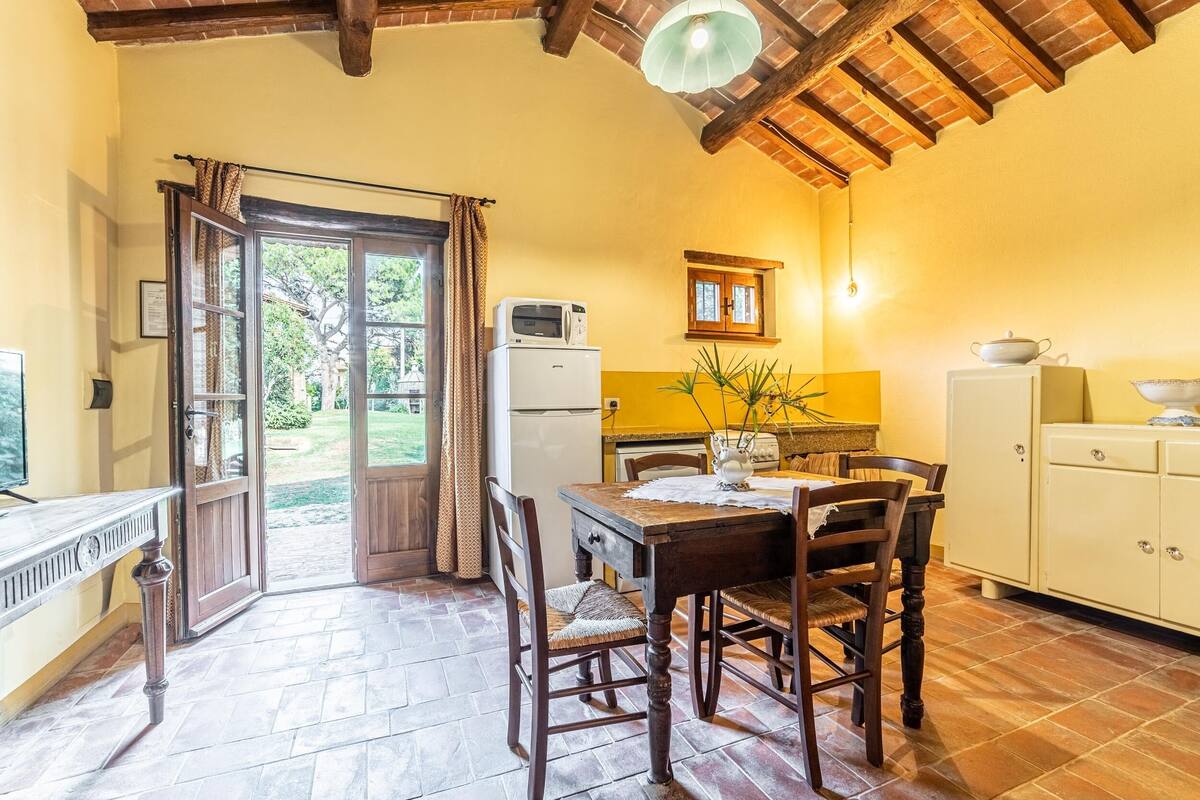 A cozy kitchen with a dining table, chairs, a refrigerator, and a window with curtains.