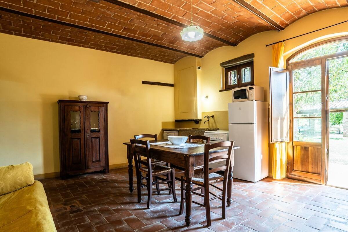 A kitchen with a wooden table, chairs, a cabinet, and a refrigerator.
