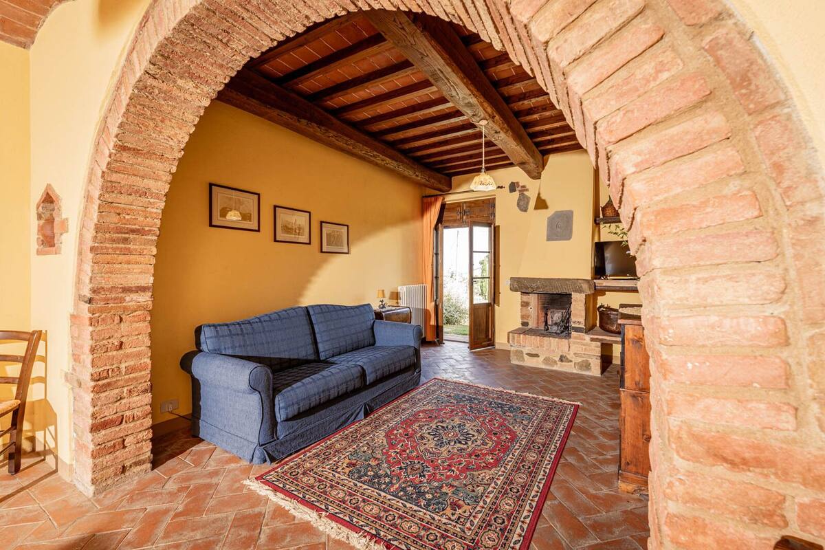 A cozy living room with a blue sofa, a patterned rug, and a stone fireplace.