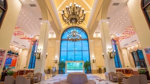 A spacious lobby with a large chandelier, a reception desk, and a view through a large arched window. - Yinghai Hotel Apartment Zhuhai Chimelong (Zhuhai)