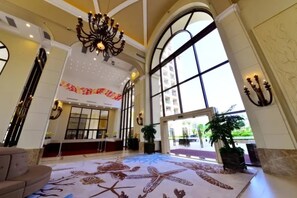 Un'ampia hall con soffitto alto, grandi finestre e un lampadario.