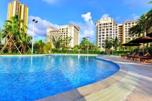 Una piscina circondata da palme e alti edifici.